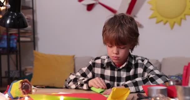 Niño plegando un avión de papel y barcos, niño causasiático jugando con aviones de papel, futuro ingeniero diseñador, hobby — Vídeos de Stock