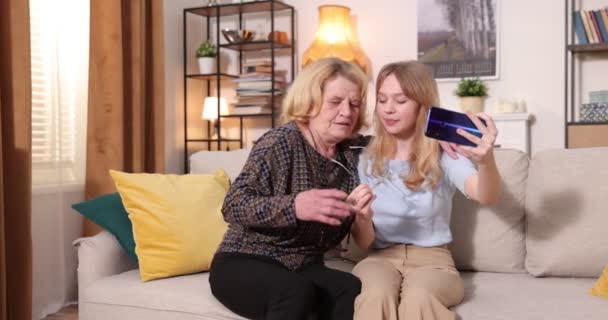 Happy grandmother with her granddaughter. He relaxes at home together. Resting on the couch. Two generations of grandparents and grandchildren spend time together — Stock Video
