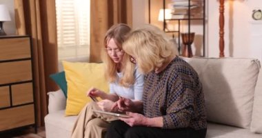 Küçük torun, büyükannesine kredi kartıyla alışveriş yapmayı öğretiyor ve dizüstü bilgisayarını işaret ediyor.