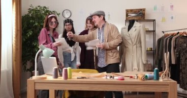 Moda tasarımcılarının ve terzilerin işi. Moda tasarımcıları stüdyolarında çalışıyor. Renkli Kumaşlar, Giysiler Asılma ve Dikiş Ögeleri Görünür.