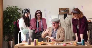 Moda tasarımcılarının ve terzilerin işi. Moda tasarımcıları stüdyolarında çalışıyor. Renkli Kumaşlar, Giysiler Asılma ve Dikiş Ögeleri Görünür