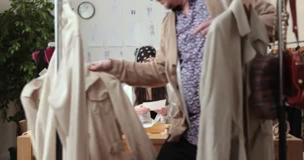 Het werk van modeontwerper en kleermakers in de winkel. Modeontwerpers werken in hun atelier. Kleurrijke stoffen, kleding opknoping en naaiwerk zijn zichtbaar. — Stockvideo