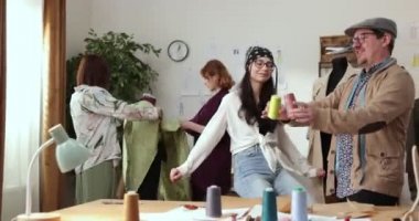 Moda tasarımcılarının ve terzilerin işi. Moda tasarımcıları stüdyolarında çalışıyor. Renkli Kumaşlar, Giysiler Asılma ve Dikiş Ögeleri Görünür.