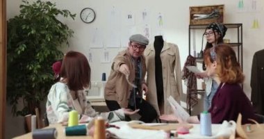 Moda tasarımcılarının ve terzilerin işi. Moda tasarımcıları stüdyolarında çalışıyor. Renkli Kumaşlar, Giysiler Asılma ve Dikiş Ögeleri Görünür.