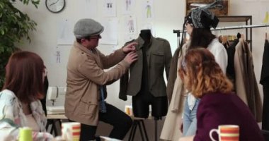 Moda tasarımcılarının ve terzilerin işi. Moda tasarımcıları stüdyolarında çalışıyor. Renkli Kumaşlar, Giysiler Asılma ve Dikiş Ögeleri Görünür.