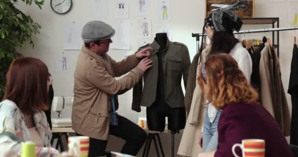 Modeskaparens och skräddarnas arbete i butiken. Modeskapare som arbetar i sin studio. Färgglada tyger, kläder hängning och syartiklar är synliga. — Stockvideo