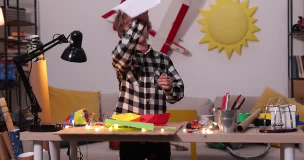 Jonge jongen vouwen een papieren vliegtuig en schepen, causasian jongen spelen met papieren vliegtuigen, toekomstige ingenieur ontwerper, hobby — Stockvideo