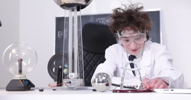 Onderwijs, wetenschap en kinderen concept - jongen draagt een bril voor natuurkunde lab doet elektrische tests. Kind bestudeert elektrische ontladingen in een lab. — Stockvideo