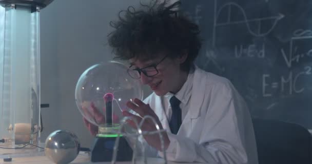 Образование, наука и детская концепция - мальчик в очках для лаборатории физики, проводящий электрические тесты. Ребенок изучает электрические разряды в лаборатории. — стоковое видео