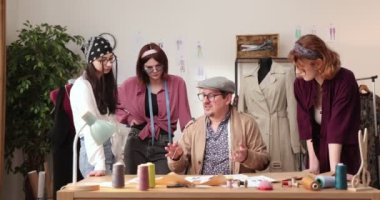 Moda tasarımcılarının ve terzilerin işi. Moda tasarımcıları stüdyolarında çalışıyor. Renkli Kumaşlar, Giysiler Asılma ve Dikiş Ögeleri Görünür