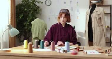 Moda tasarımcılarının ve terzilerin işi. Moda tasarımcıları stüdyolarında çalışıyor. Renkli Kumaşlar, Giysiler Asılma ve Dikiş Ögeleri Görünür.