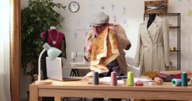 Moda tasarımcılarının ve terzilerin işi. Moda tasarımcıları stüdyolarında çalışıyor. Renkli Kumaşlar, Giysiler Asılma ve Dikiş Ögeleri Görünür