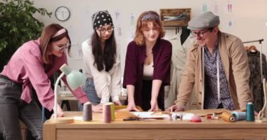 Moda tasarımcılarının ve terzilerin işi. Moda tasarımcıları stüdyolarında çalışıyor. Renkli Kumaşlar, Giysiler Asılma ve Dikiş Ögeleri Görünür