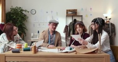 Moda tasarımcılarının ve terzilerin işi. Moda tasarımcıları stüdyolarında çalışıyor. Renkli Kumaşlar, Giysiler Asılma ve Dikiş Ögeleri Görünür.