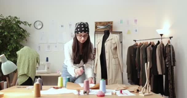 Práce módního návrháře a krejčího v obchodě. Módní návrháři pracující ve svém studiu. Barevné tkaniny, oblečení Závěsné a šicí předměty jsou viditelné. — Stock video