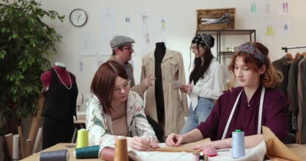 The work of fashion designer and tailors in the shop. Fashion designers working in their studio. Colorful Fabrics, Clothes Hanging and Sewing Items are Visible. — Stock Video