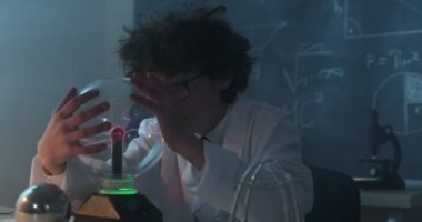 Fizik dersinde deneyler yapan bir öğrenci. Sınıfta fizik deneyi yapan genç bir öğrenci.