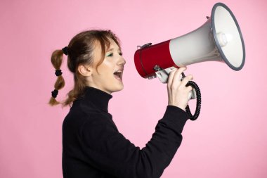 Megafonla bağıran komik genç bayan. Genç bir kadın renkli arkaplanda hoparlör kullanıyor.