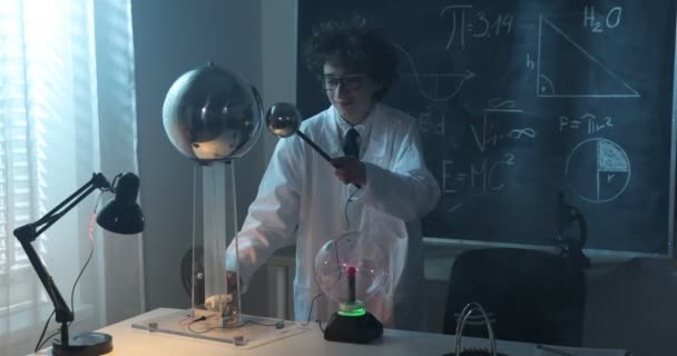 Un garçon mène des expériences physiques avec de l'électricité, une boule de plasma et un générateur Van de Graaff. — Video