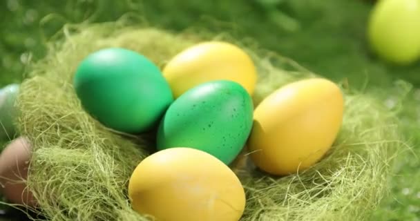 Huevos de Pascua coloridos en la hierba. Vista superior giratoria de huevos de Pascua de colores acostados sobre fondo verde de Pascua. — Vídeo de stock