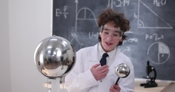 Az iskolás fiú fizika órán kísérletezik. Fiatal diák csinál fizika kísérlet az osztályteremben. — Stock videók
