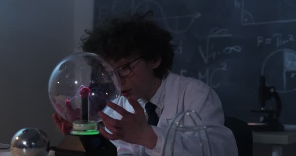 Un garçon mène des expériences physiques avec de l'électricité, une boule de plasma et un générateur Van de Graaff. — Video