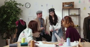 Moda tasarımcılarının ve terzilerin işi. Moda tasarımcıları stüdyolarında çalışıyor. Renkli Kumaşlar, Giysiler Asılma ve Dikiş Ögeleri Görünür.