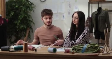 Moda tasarımcılarının ve terzilerin işi. Moda tasarımcıları stüdyolarında çalışıyor. Renkli Kumaşlar, Giysiler Asılma ve Dikiş Ögeleri Görünür.