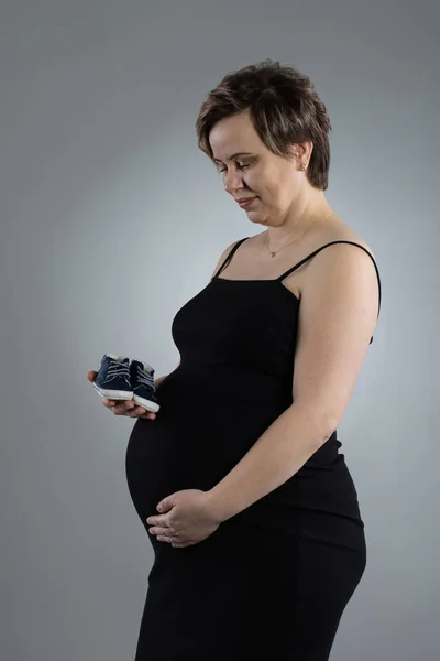 Портрет беременной женщины. Беременная счастливая Женщина трогает живот, делает фотосессию в студии — стоковое фото