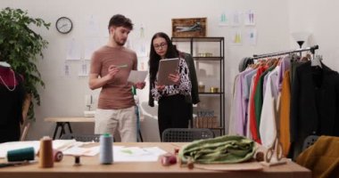 Moda tasarımcılarının ve terzilerin işi. Moda tasarımcıları stüdyolarında çalışıyor. Renkli Kumaşlar, Giysiler Asılma ve Dikiş Ögeleri Görünür.