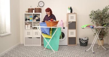 Çamaşır kurutma makinesine asılan bir kadın. Çamaşır. Ev işi kavramı.