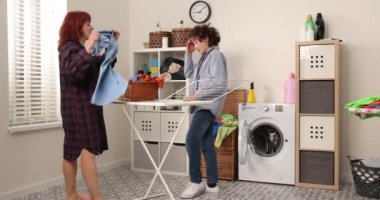 Çamaşır makinesiyle ya da çamaşır kurutma makinesiyle anne ve çocuk çamaşır odasında. Aile işleri. Çamaşırları kuru askısına yıka..
