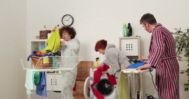 Aile çamaşırhanede birlikte çalışıyor. 4K görüntüler, anne, baba ve oğul çamaşır odasında ev işlerine yardım ediyor.