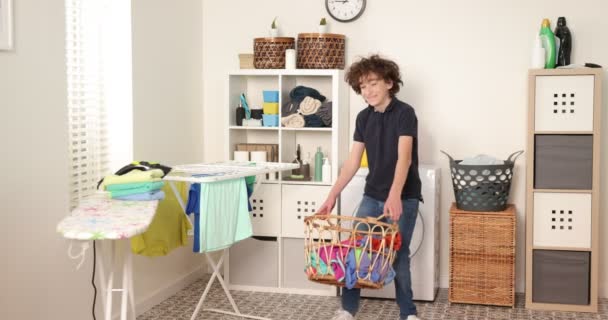Chlapec si hraje s oblečením během praní. Mladý dospívající chlapec házet koš s prádlem — Stock video