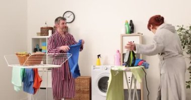 Aile çamaşırhanede birlikte çalışıyor. 4K görüntüler, anne, baba ve oğul çamaşır odasında ev işlerine yardım ediyor.