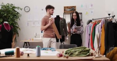 Moda tasarımcılarının ve terzilerin işi. Moda tasarımcıları stüdyolarında çalışıyor. Renkli Kumaşlar, Giysiler Asılma ve Dikiş Ögeleri Görünür.