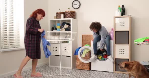 Mutter und Sohn spielen Hausarbeit. Familie hat Spaß beim Kleideraufhängen in der Waschküche. — Stockvideo