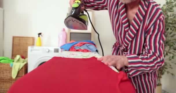 Καυκάσιος σιδερώνει ρούχα στο πλυσταριό. Τακτοποιημένος άνδρας σιδερώνει πουκάμισο στο σπίτι, επιμελής σύζυγος κάνει δουλειές του σπιτιού, πλυντήριο — Αρχείο Βίντεο