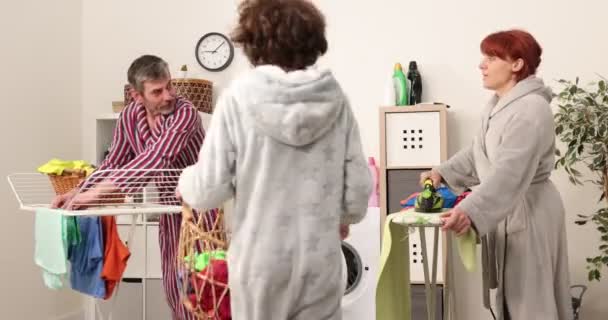 A család együtt dolgozik a mosókonyhában. 4k felvételek, anya, apa és fia segít a házimunkában a mosodában — Stock videók