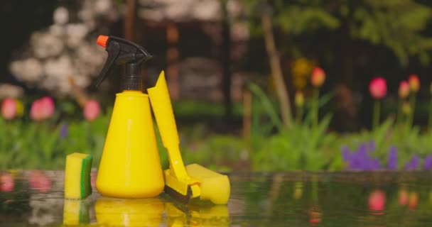 Gereedschap voor het reinigen van ramen tegen een achtergrond van een lentetuin. Huishoudelijk concept — Stockvideo