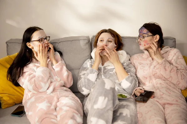 Tres chicas jóvenes lindas menores de 20 años en colorido pijama divertido divertirse mientras que en pijamas niñas —  Fotos de Stock