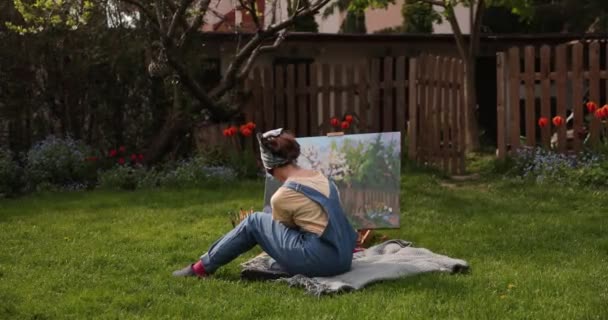 Tonåring flicka målning på duk i trädgården . — Stockvideo