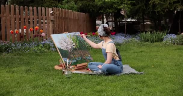 Glimlachend meisje schilderen op doek met aquarellen in de tuin — Stockvideo