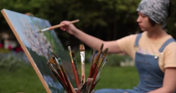 Jonge vrouw schilderij bloemen in de tuin — Stockvideo