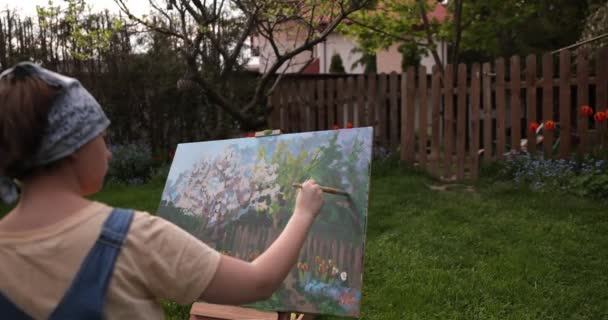 Nastolatka malowanie na płótnie w ogrodzie . — Wideo stockowe