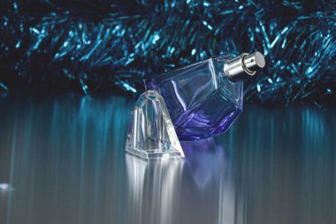 Geometrik mor parfüm şişesi mavi renkli bir fonda yansıması var. Noel havası.