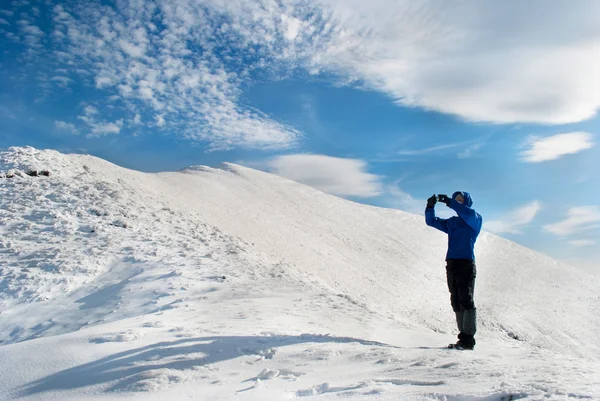 Wanderer-Fotograf fotografiert vor schneebedeckten Bergen — Stockfoto
