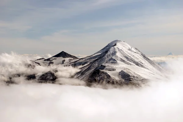 Две вершины вулкана, покрытые снегом в облаках Лицензионные Стоковые Фото