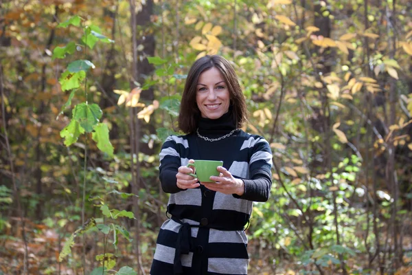 Junge Dame mit grüner Tasse Tee im Herbstwald — Stockfoto