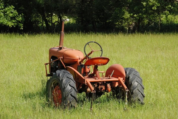 Oude trekker in een veld — Stockfoto